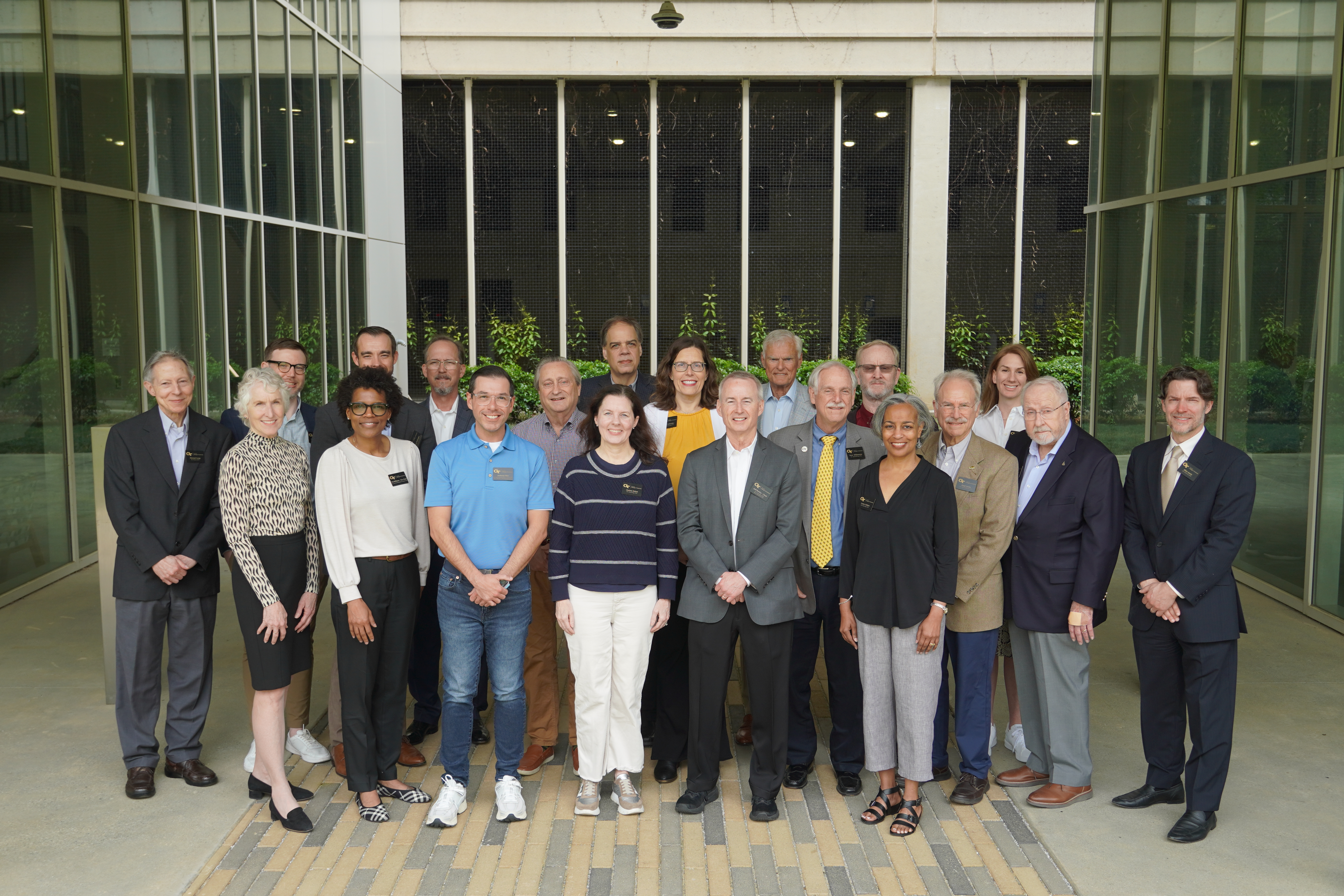 The COS Advisory Board members in a line on top of the Kendeda building, with the overcast Atlanta skyline behind them